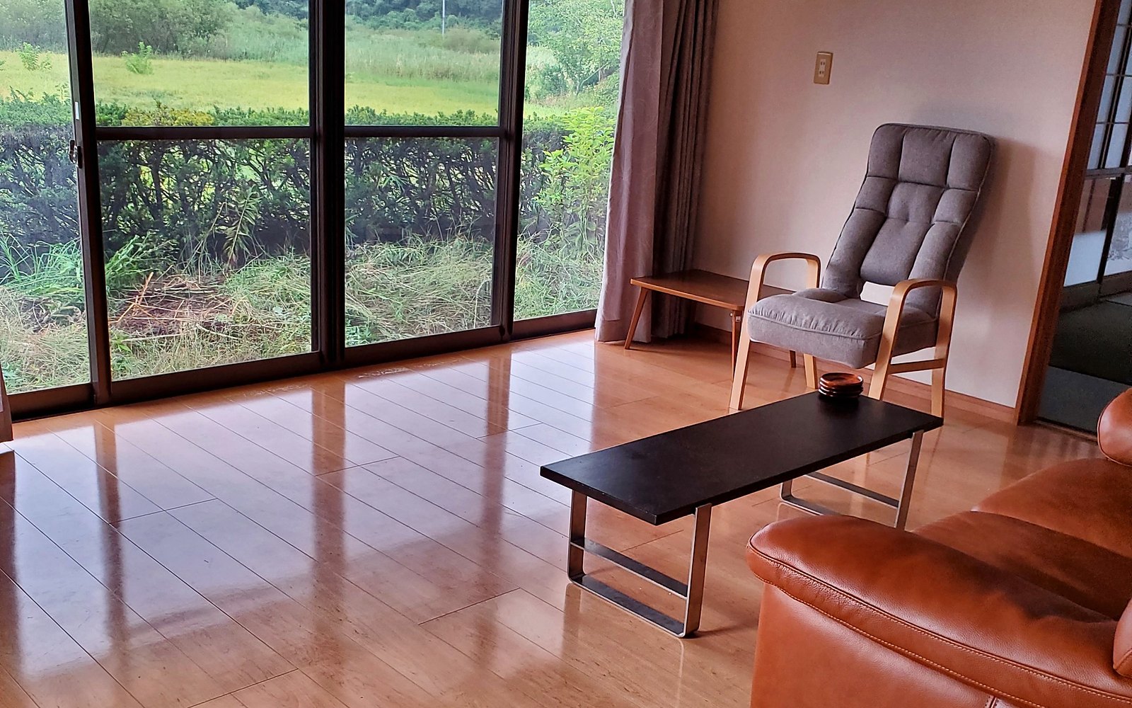 The living room at Kichi Itako, a wall of glass looking out over green fields